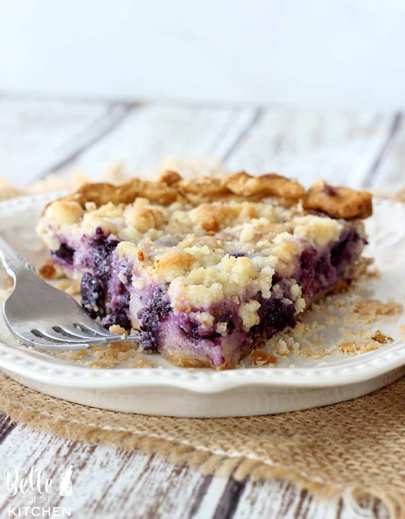 A close up of a piece of pie on a plate, with blueberries
