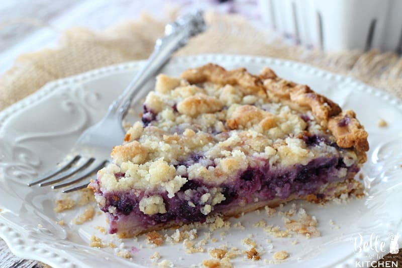 A close up of a piece of pie on a plate, with blueberries