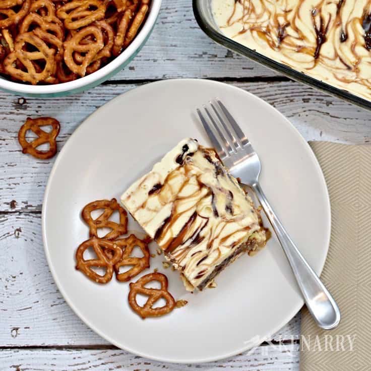 dish of ice cream cake beside a bowl of pretzels and a plate with a fork and slice of cake