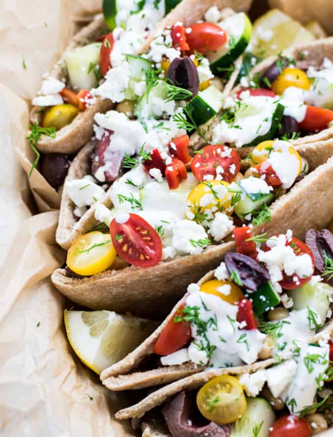 A close up of food, with Pitas and Steak, tomatoes, and lemons