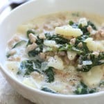 A bowl of soup with potatoes, kale, and sausage