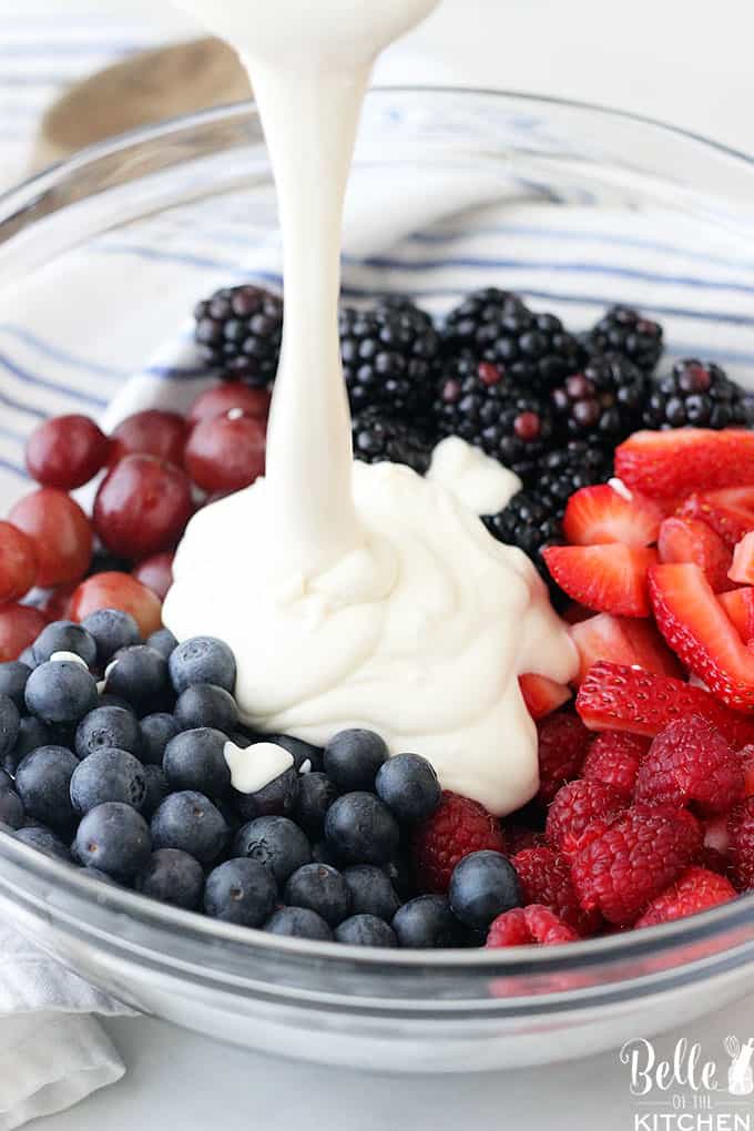 A bowl of fruit with greek yogurt being poured on top