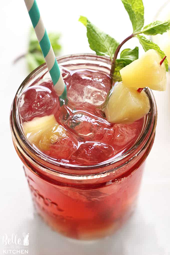 A close up of a glass of tea with chopped pineapple and mint