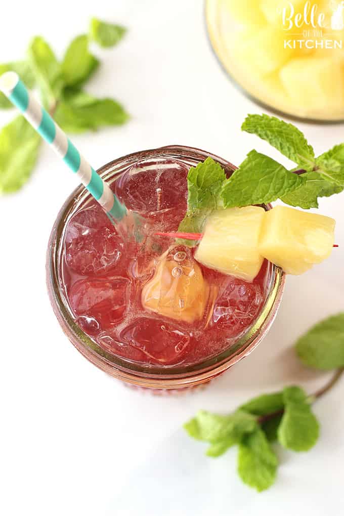 A glass of tea on a table in a mason jar with pineapple and mint