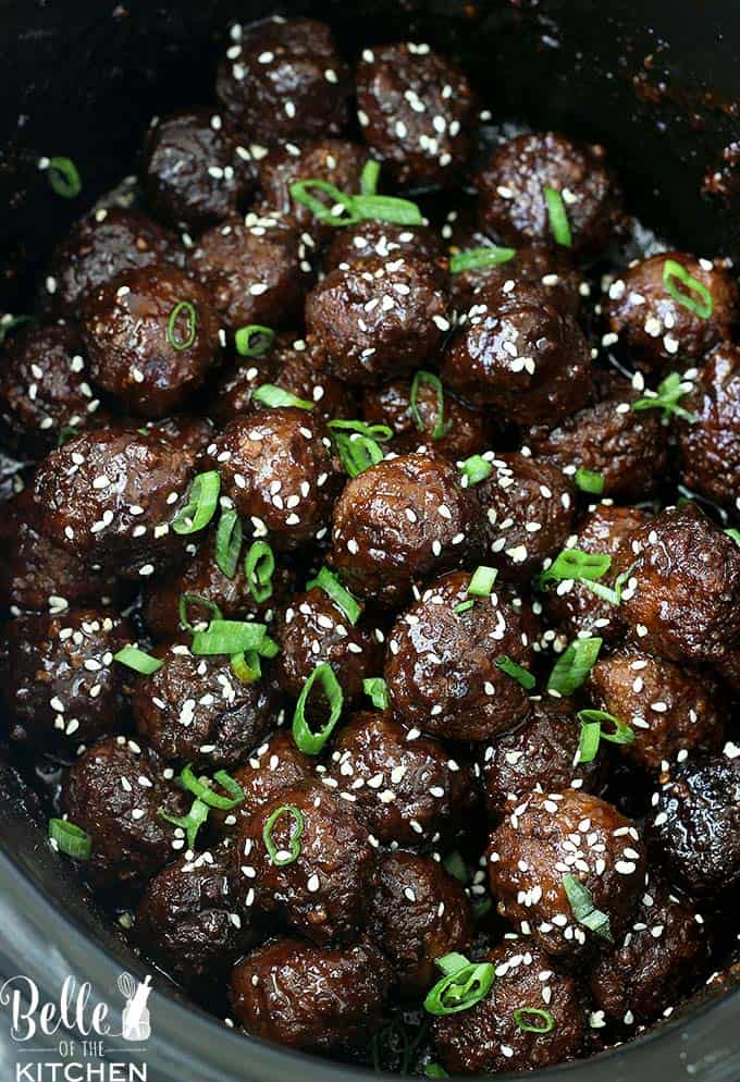 A close up of meatballs with sesames seeds and green onions sprinkled on top