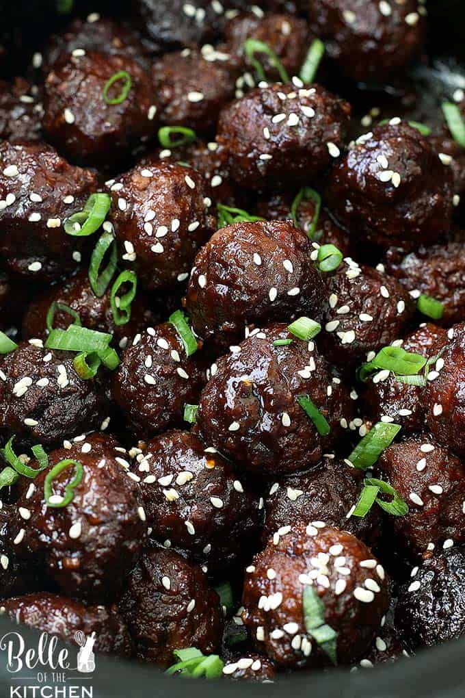 A close up of meatballs with sesames seeds and green onions sprinkled on top