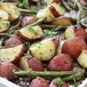 A close up of Pesto and Potatoes with green beans on a sheet pan
