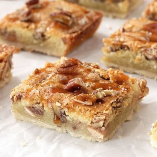 This Caramel Pecan Slab Pie is the perfect dessert for the holidays! A buttery crust is topped with crunchy pecans and a sweet caramel filling, then baked on a sheet pan. Cut into slices and top them with whipped cream and a drizzle of caramel for a truly decadent dessert!