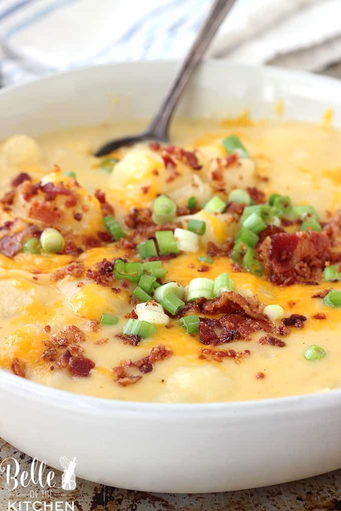 A bowl of potato soup with bacon, green onions, and cheese