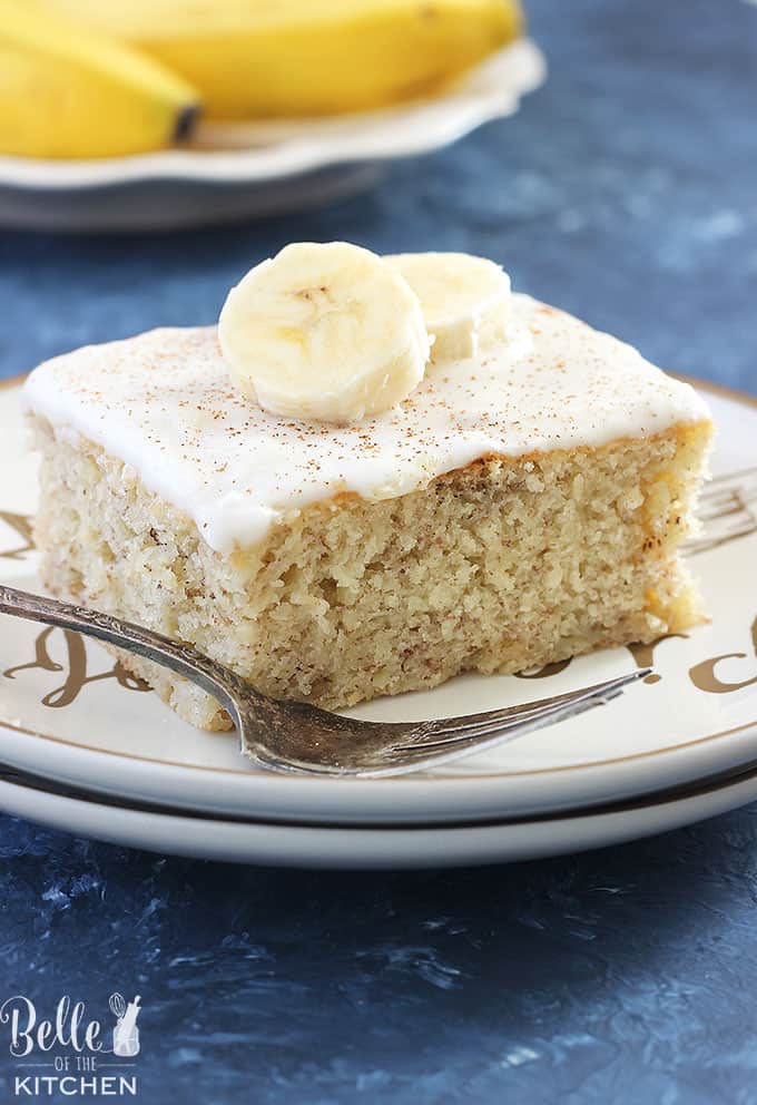 A piece of cake on a plate with bananas on top and a fork on the side