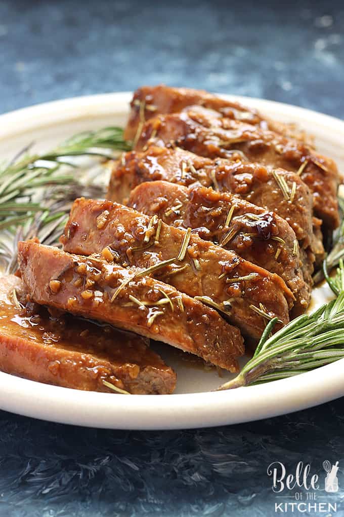 A plate of sliced pork tenderloin with rosemary on the side