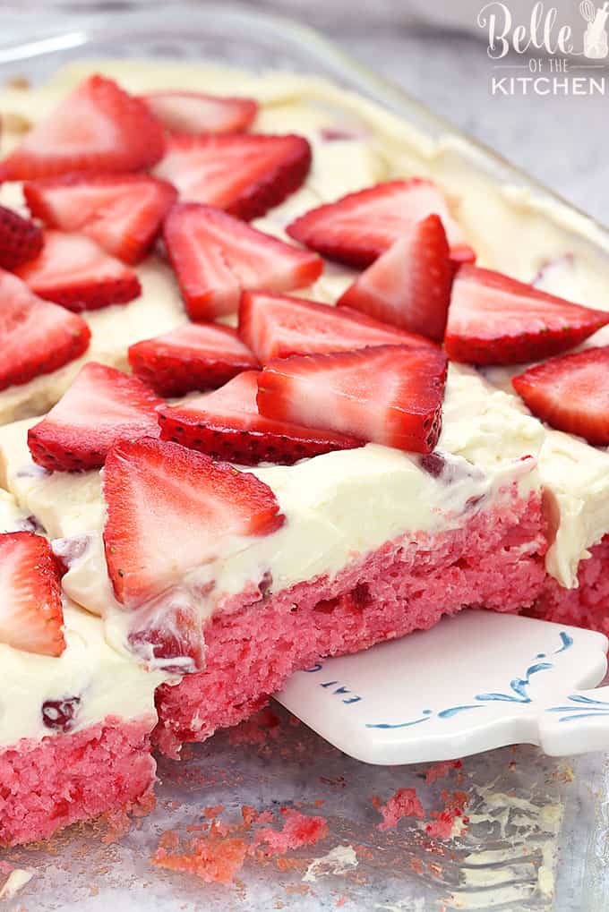 A closeup of strawberry cake with frosting and chopped strawberries on top