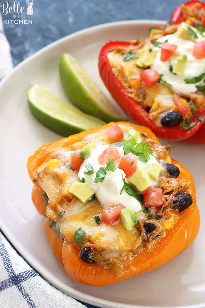 A plate of peppers sliced in half filled with chicken enchilada filling and slice lime on the side
