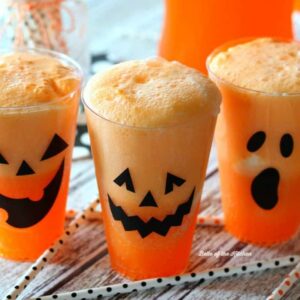 cups filled with Fanta, vanilla ice cream, and jack o'lantern faces on the side of the cups