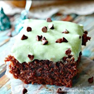 A close up of a piece of chocolate brownies topped with mint frosting and chocolate chips