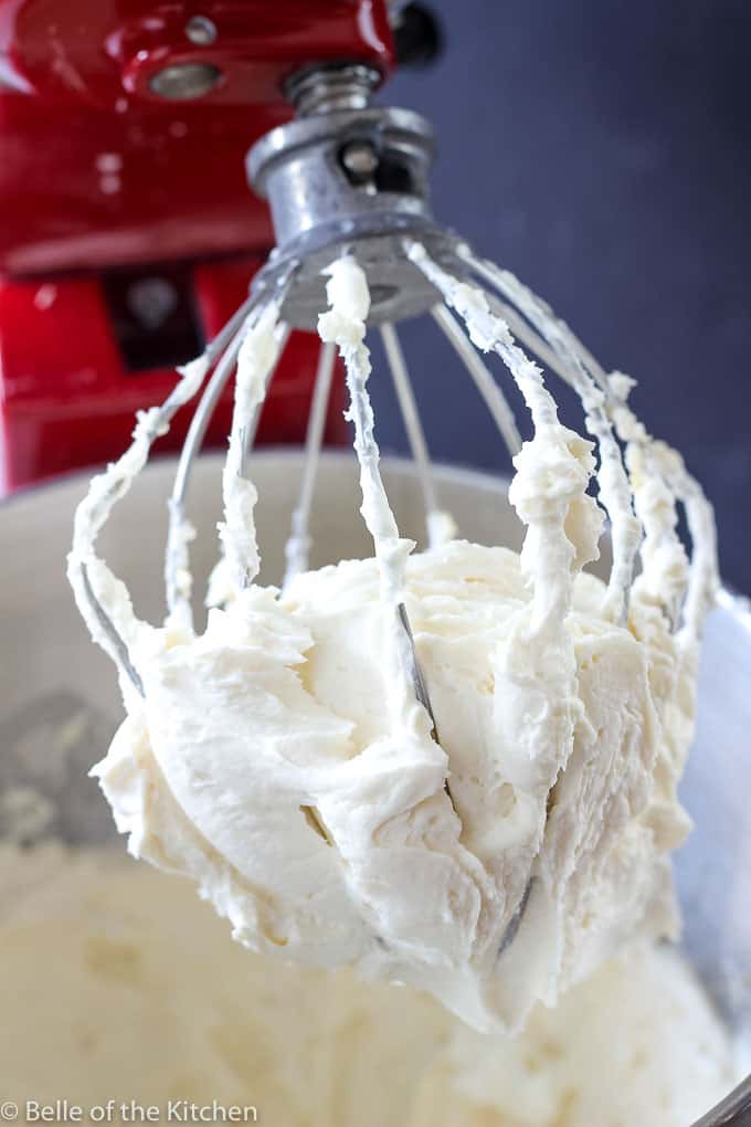 A close up of vanilla frosting on a whisk attachment