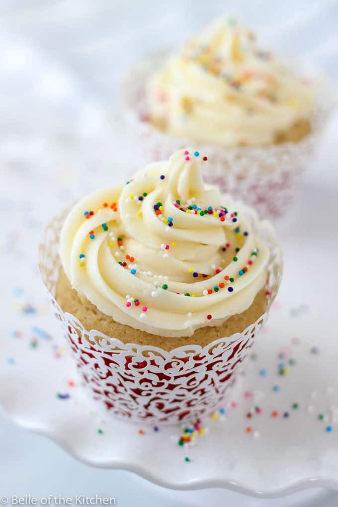 A close up of a vanilla cupcake with sprinkles on top