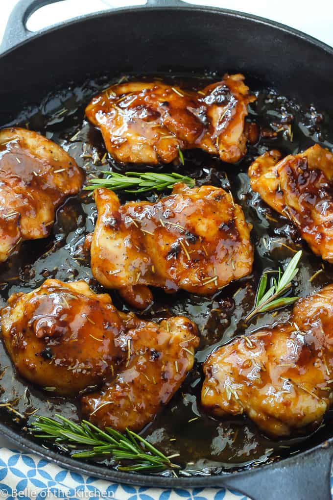 A pan filled with chicken, sauce, and rosemary sprigs