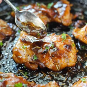 A close up of a piece of chicken being drizzled with sauce