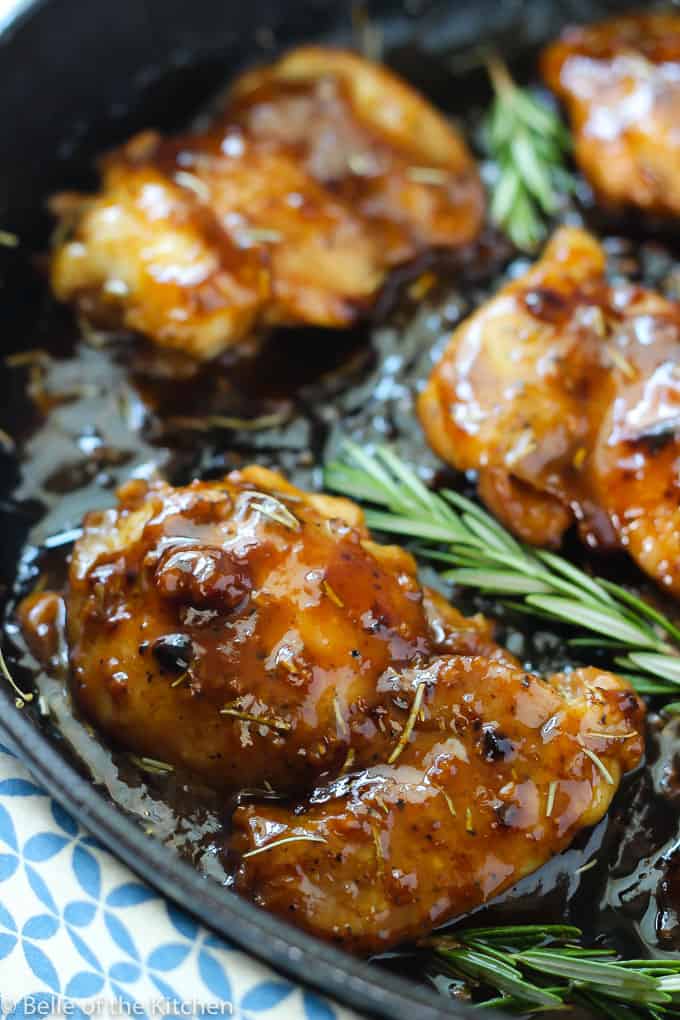 A pan filled with chicken, sauce, and rosemary sprigs