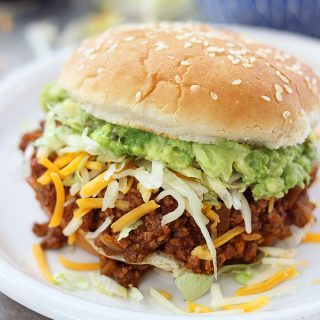 A sloppy Joe sandwich with lettuce and cheese on a plate