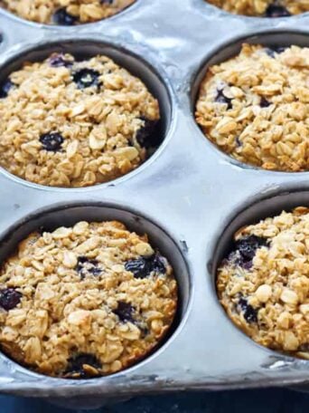 a muffin tin filled with baked blueberry oatmeal cups