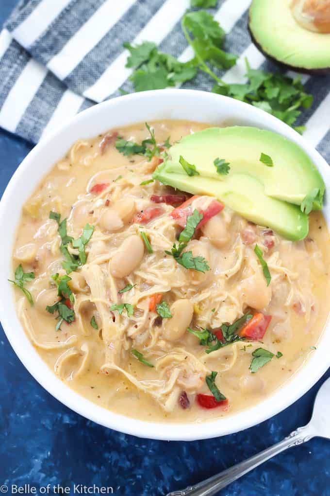 A bowl of soup with beans, avocado, and chicken