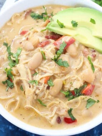 A bowl of soup with beans, avocado, and chicken