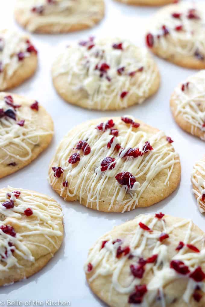 A close up of cookies topped with cranberries and drizzled icing