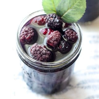mason jar filled with blackberry sweet tea and frozen blackberries
