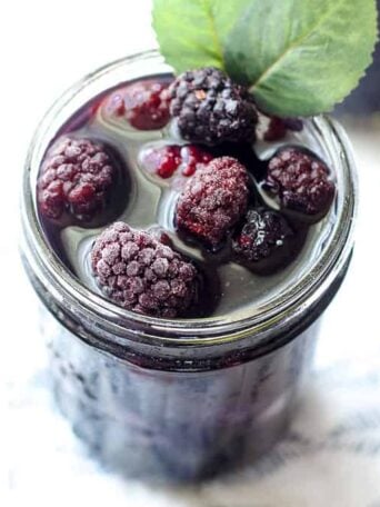 mason jar filled with blackberry sweet tea and frozen blackberries