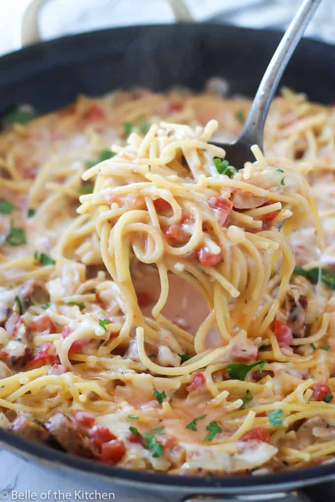 A spoonful of noodles with sauce, sausage, and tomatoes