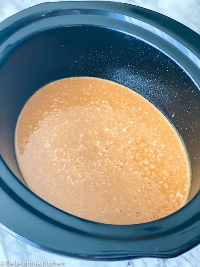 A close up of a crockpot bowl with cake batter