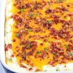 A dish of mashed potatoes covered in cheese and bacon
