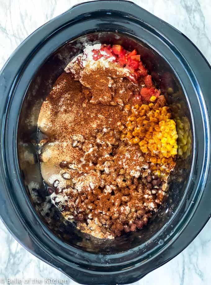 black crockpot bowl full of shredded chicken, cream cheese, black beans, corn, and salsa