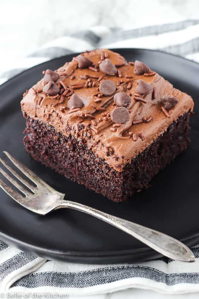 chocolate cake on a black plate with a fork next to it
