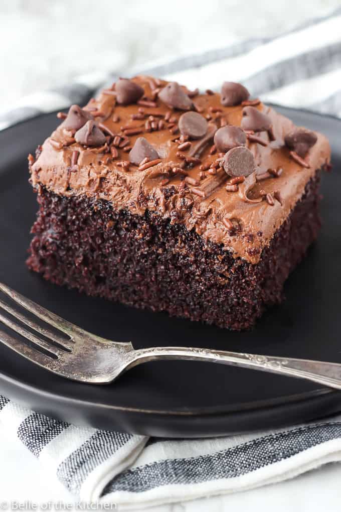 chocolate cake on a black plate with a fork next to it