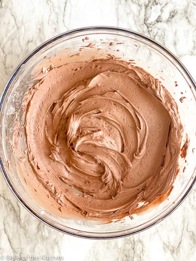 overhead shot of whipped chocolate buttercream frosting in a glass bowl