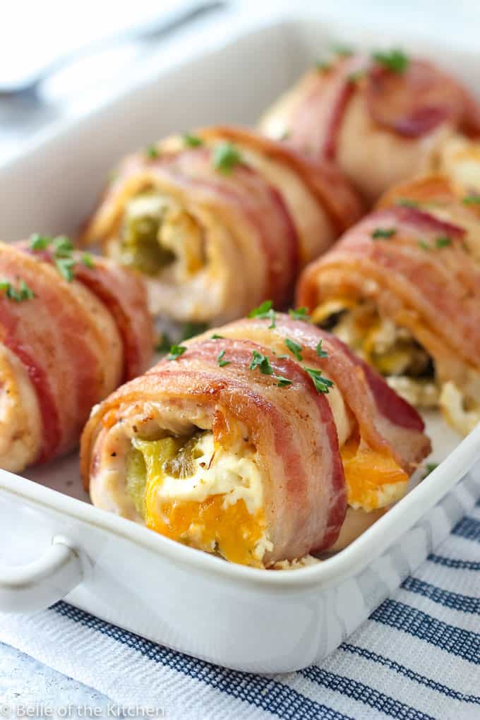 a white baking dish filled with chicken breasts wrapped in bacon