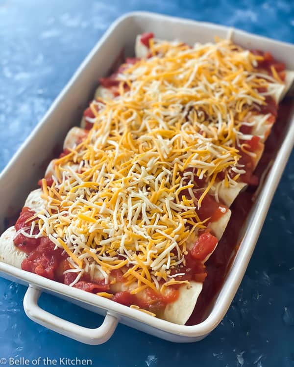 white rectangle baking dish with enchiladas topped with cheese