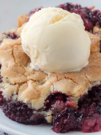 a plate with blackberry cobbler and vanilla ice cream on top