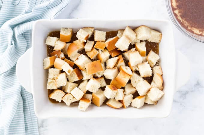 a white baking dish full of cubed french bread