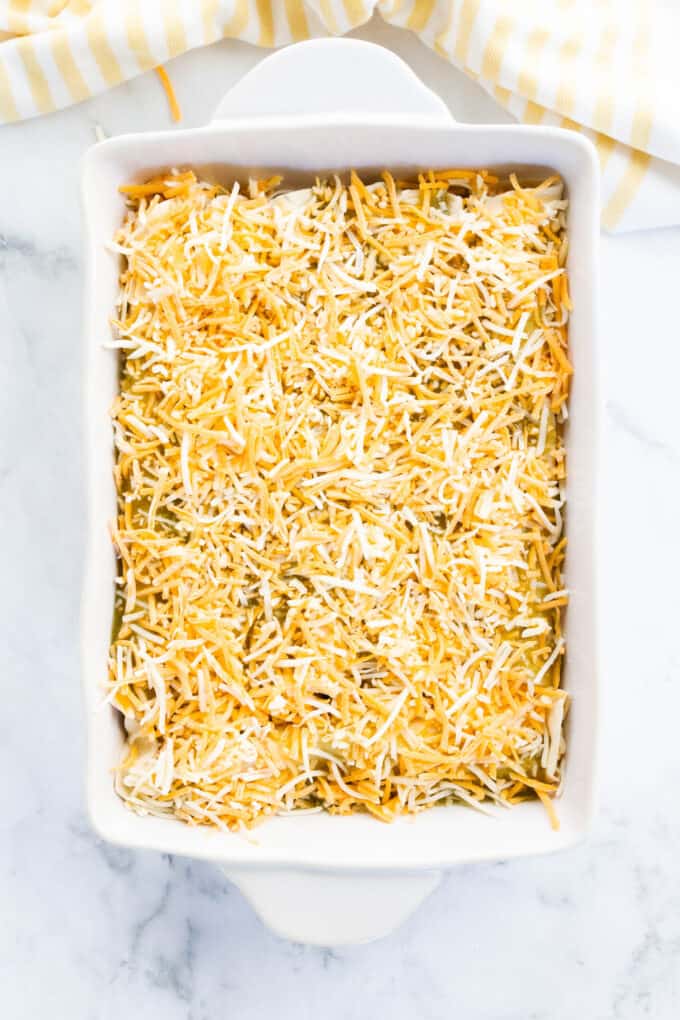 a baking dish filled with enchiladas and topped with shredded cheese