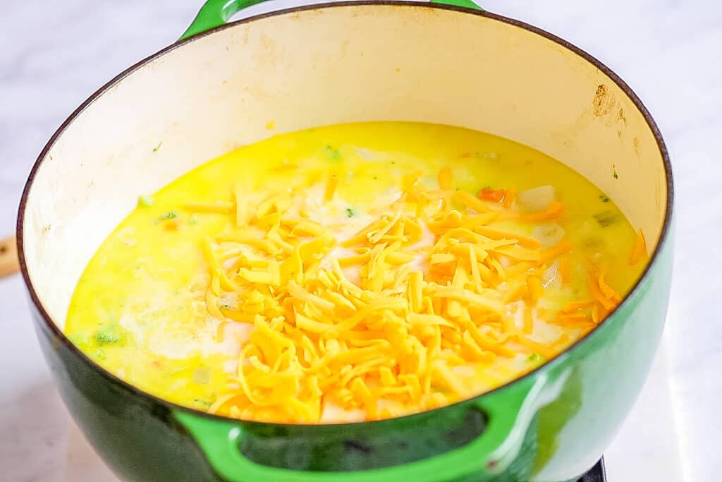 a large pot full of soup with shredded cheese on top
