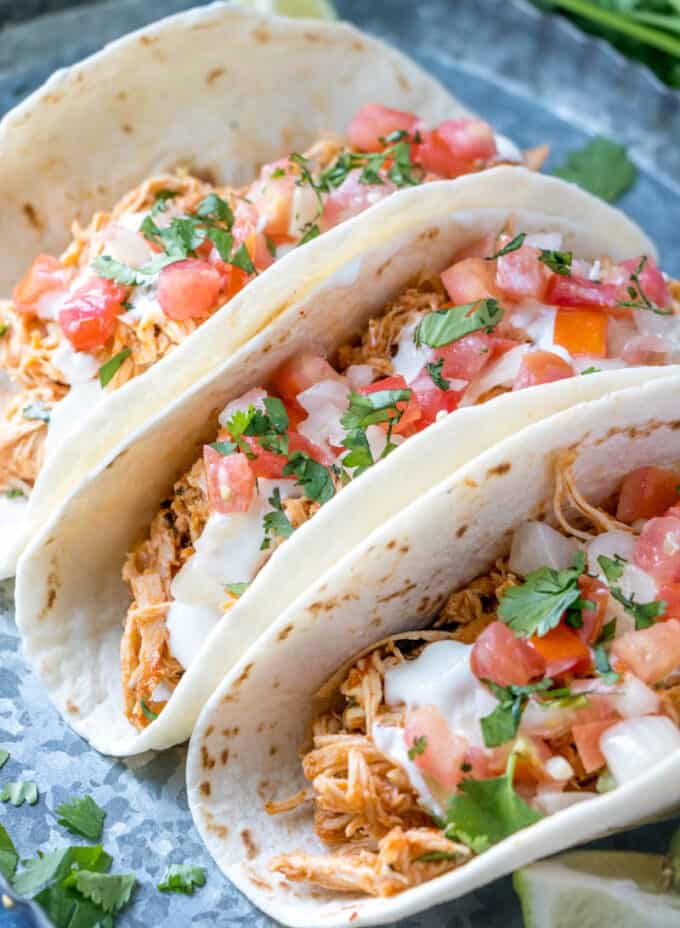 chicken tacos on a platter topped with pico and cilantro