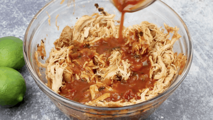 shredded chicken in a bowl with poured sauce