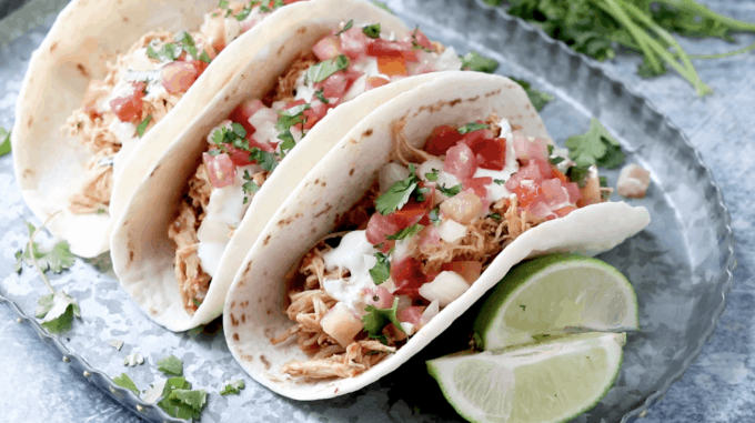 chicken tacos on a platter topped with pico and cilantro