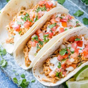 chicken tacos on a platter topped with pico and cilantro