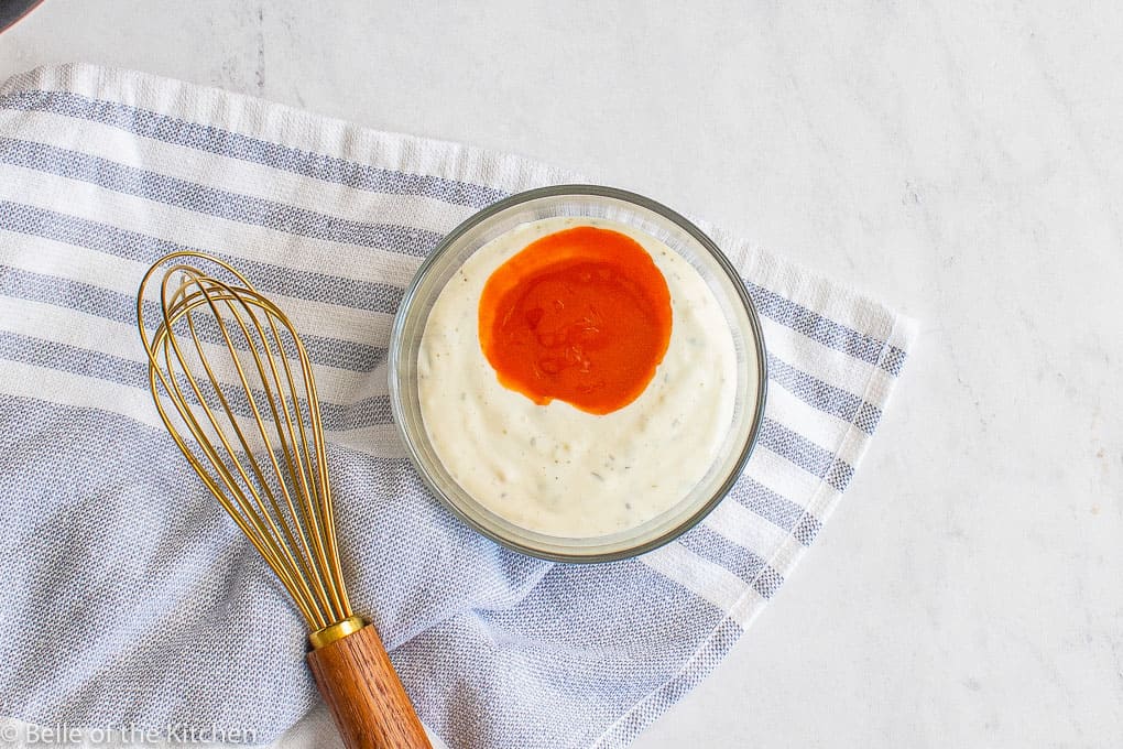 a bowl of ranch dressing next to a whisk