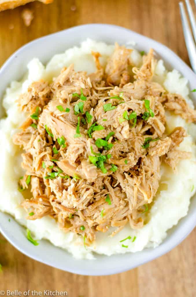 white bowl filled with mashed potatoes and shredded Mississippi chicken